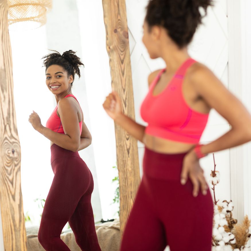 A woman looking her body reflection on a mirror.