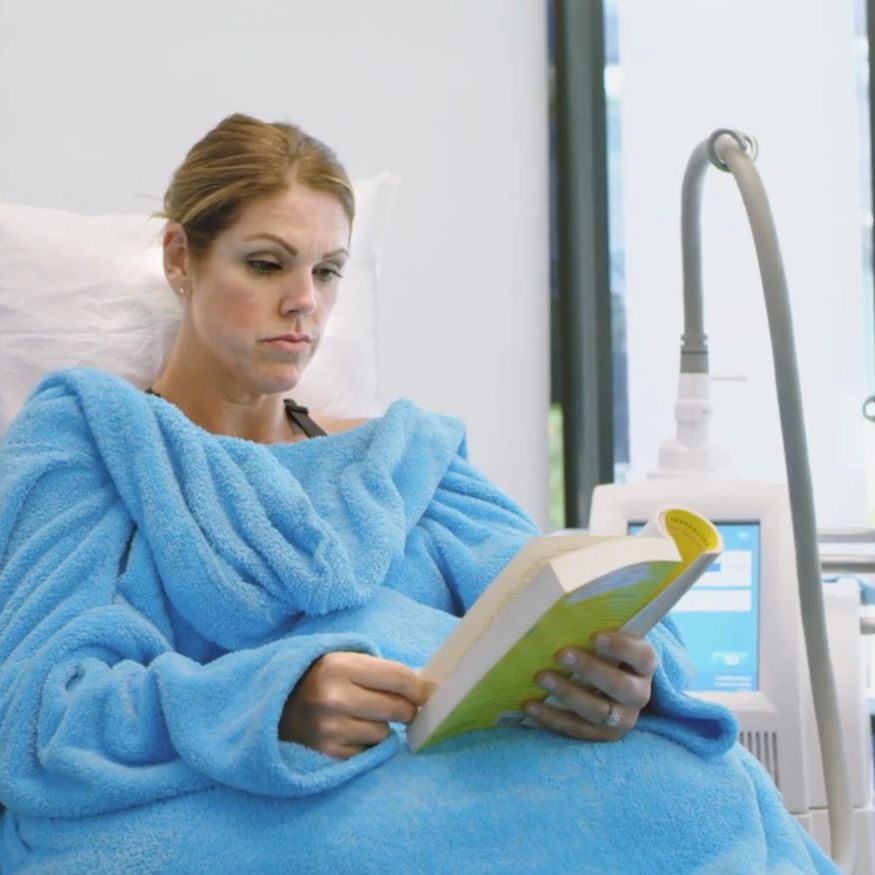 A woman patient reading a book while having a coolsculpting treatment.